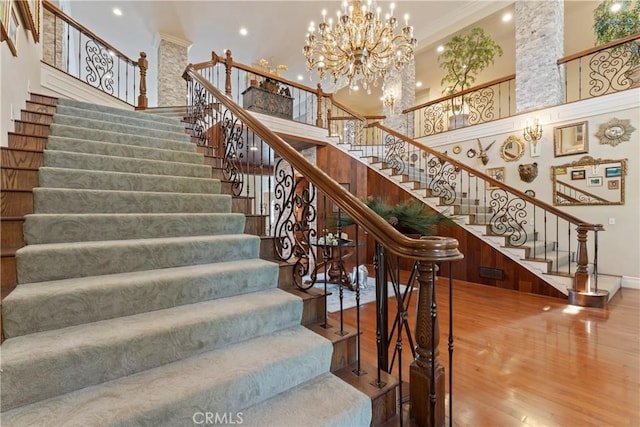 staircase featuring hardwood / wood-style flooring, a towering ceiling, and an inviting chandelier