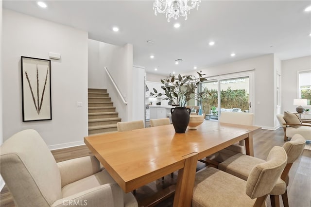 dining area with light hardwood / wood-style flooring and a notable chandelier