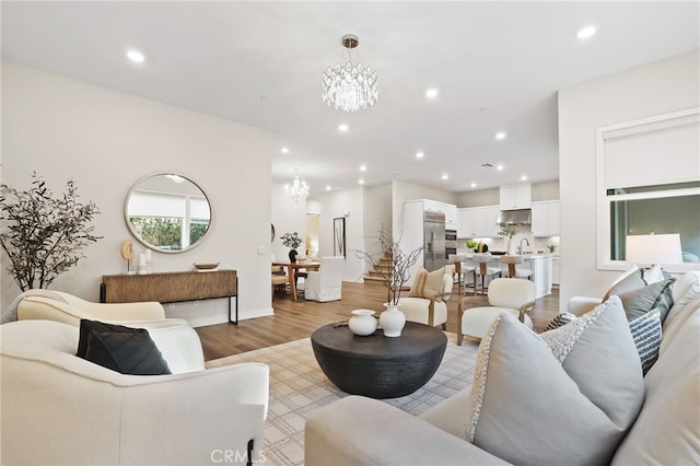 living room featuring a notable chandelier, light hardwood / wood-style floors, and sink