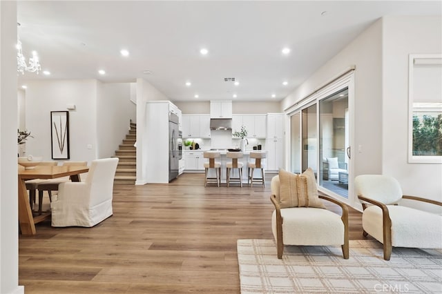 living room with light hardwood / wood-style floors and an inviting chandelier