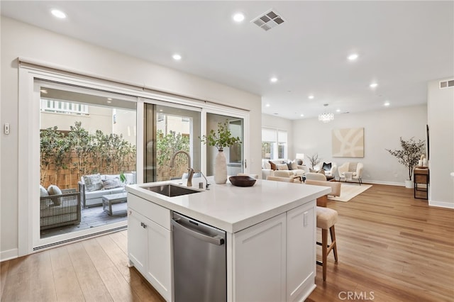 kitchen featuring white cabinetry, dishwasher, sink, a center island with sink, and light wood-type flooring