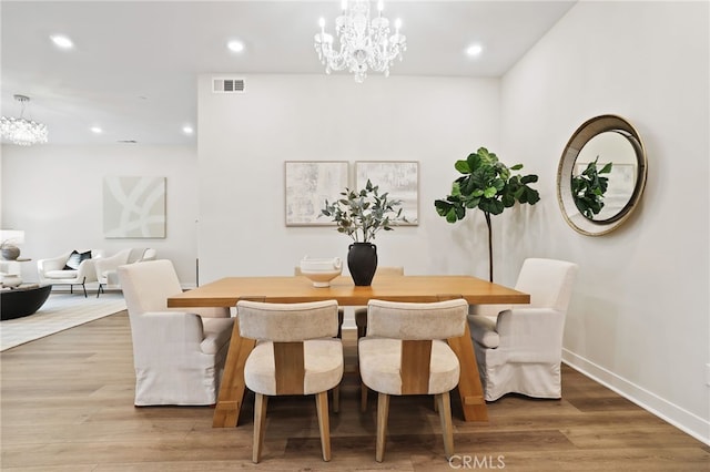 dining space featuring wood-type flooring and an inviting chandelier