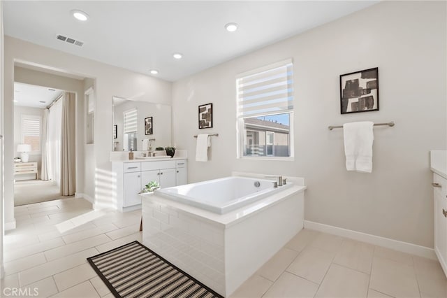 bathroom featuring tile patterned floors, tiled bath, and vanity