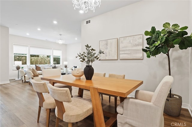 dining area with hardwood / wood-style flooring and an inviting chandelier