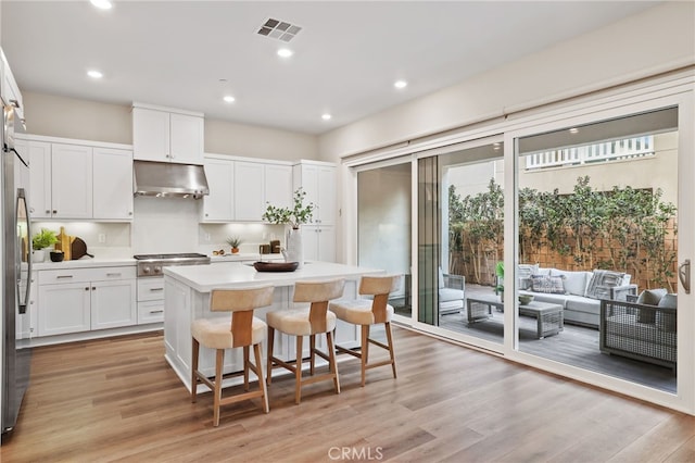 kitchen featuring a center island, white cabinetry, stainless steel appliances, and light hardwood / wood-style flooring