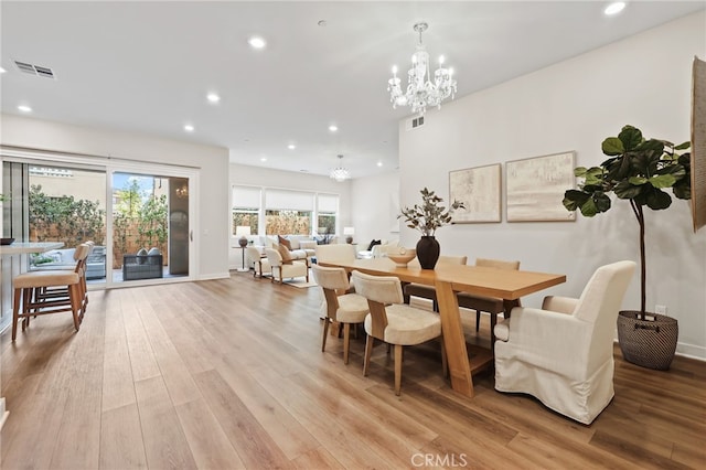 dining space featuring light hardwood / wood-style floors and a notable chandelier