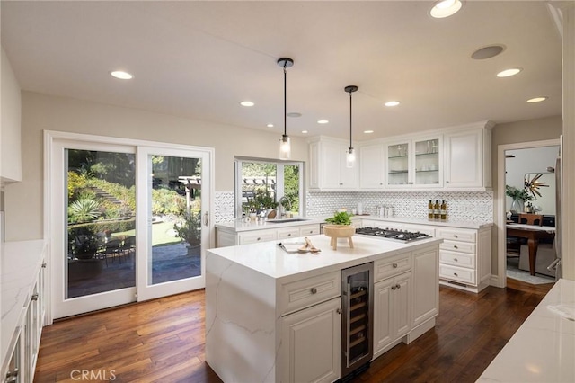 kitchen featuring a kitchen island, white cabinets, wine cooler, and hanging light fixtures