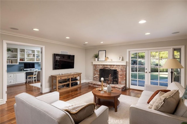 living room with crown molding, wood-type flooring, a fireplace, and french doors