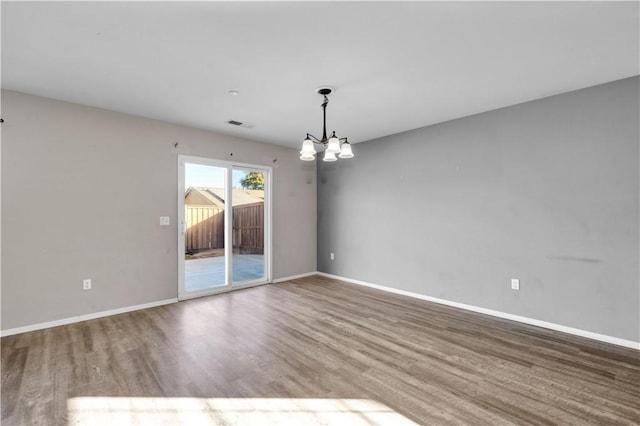 spare room with hardwood / wood-style floors and a chandelier