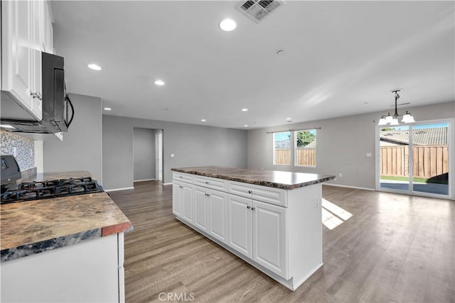 kitchen featuring a chandelier, light hardwood / wood-style floors, a kitchen island, white cabinetry, and stove