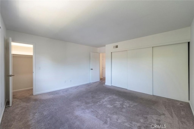 unfurnished bedroom featuring a closet and dark carpet