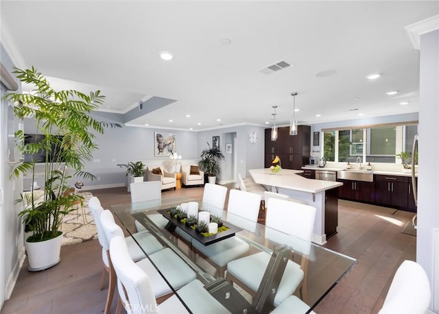 dining area with sink, dark wood-type flooring, and crown molding