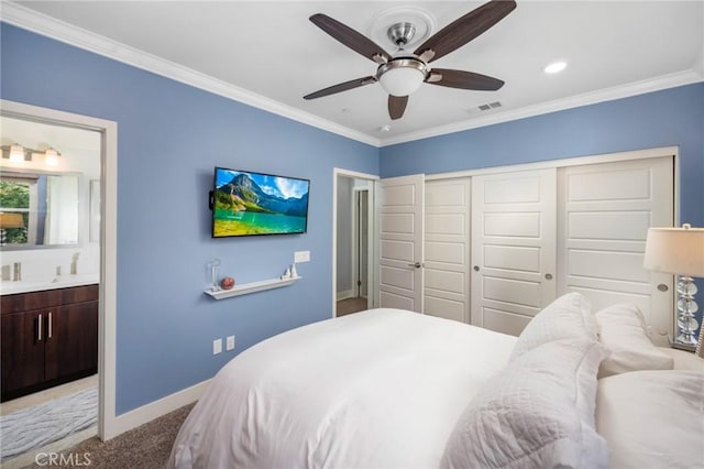 carpeted bedroom with a closet, ensuite bath, ceiling fan, and ornamental molding