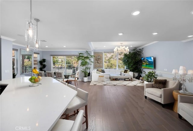 interior space with dark hardwood / wood-style flooring, a kitchen breakfast bar, hanging light fixtures, a chandelier, and crown molding