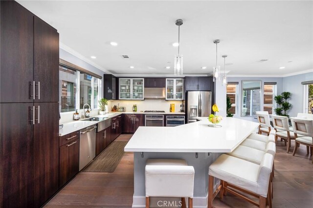 kitchen featuring a center island, decorative light fixtures, stainless steel appliances, sink, and crown molding