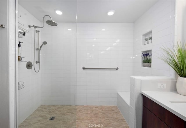 bathroom with tile walls, tiled shower, and vanity