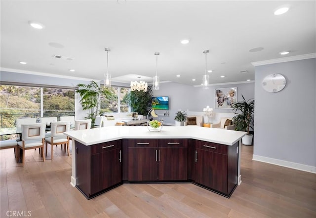 kitchen with light hardwood / wood-style floors, pendant lighting, a center island, and crown molding