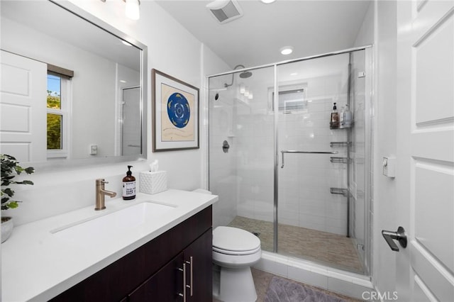 bathroom featuring vanity, toilet, and a shower with shower door