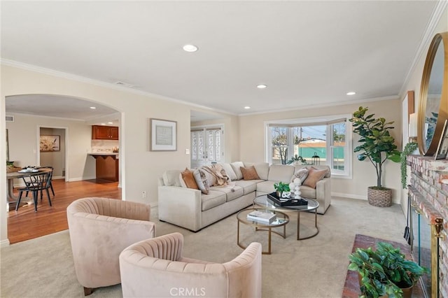 living room with a brick fireplace, light carpet, and crown molding