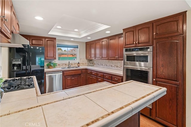 kitchen with sink, black appliances, tile countertops, and a raised ceiling