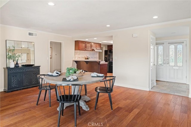 dining room with light hardwood / wood-style floors and ornamental molding