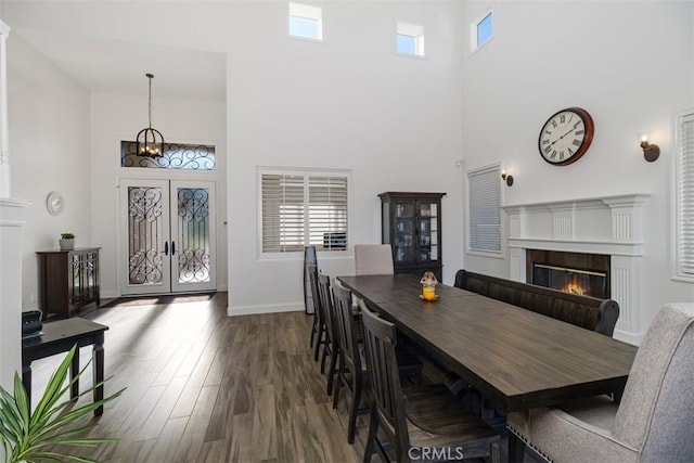 dining space featuring a towering ceiling, wood-type flooring, and french doors