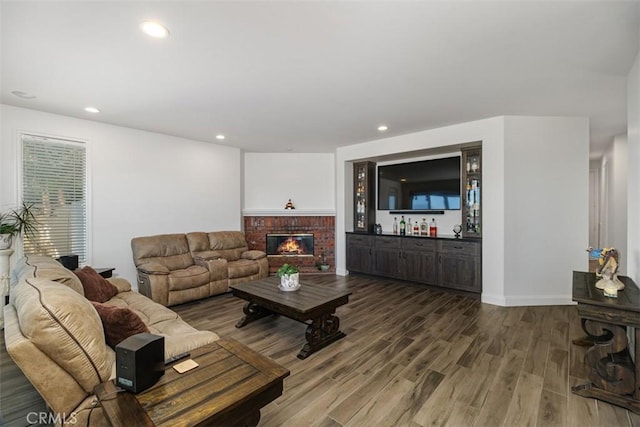 living room with a brick fireplace and hardwood / wood-style floors