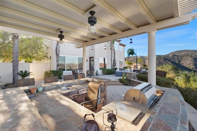 view of patio / terrace with area for grilling, ceiling fan, and a mountain view