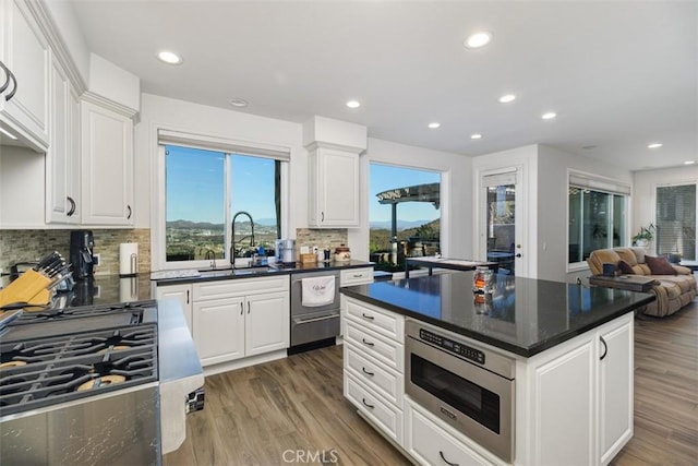 kitchen with sink, white cabinets, stainless steel microwave, and backsplash