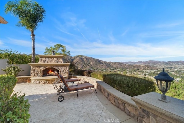 view of patio / terrace with an outdoor stone fireplace and a mountain view