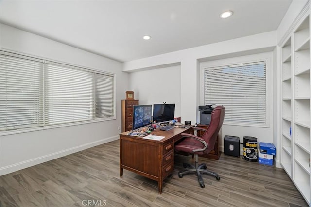 office space featuring wood-type flooring and built in shelves