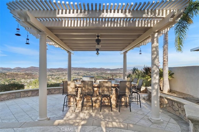 view of patio with exterior bar, a pergola, and a mountain view