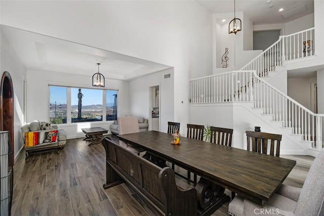 dining room with a notable chandelier, a raised ceiling, and hardwood / wood-style flooring