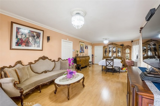 living room with crown molding, an inviting chandelier, and light wood-type flooring