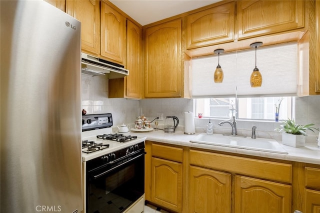 kitchen featuring gas range gas stove, sink, decorative light fixtures, fridge, and decorative backsplash