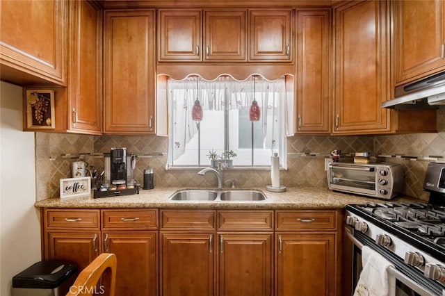 kitchen with tasteful backsplash, light stone counters, sink, and stainless steel range with gas stovetop