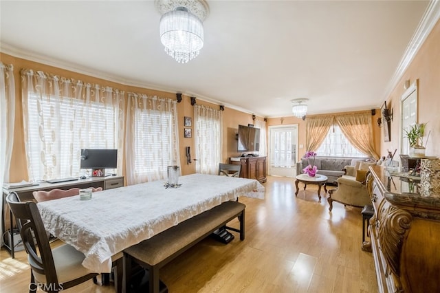 dining room with ornamental molding, light hardwood / wood-style flooring, and an inviting chandelier