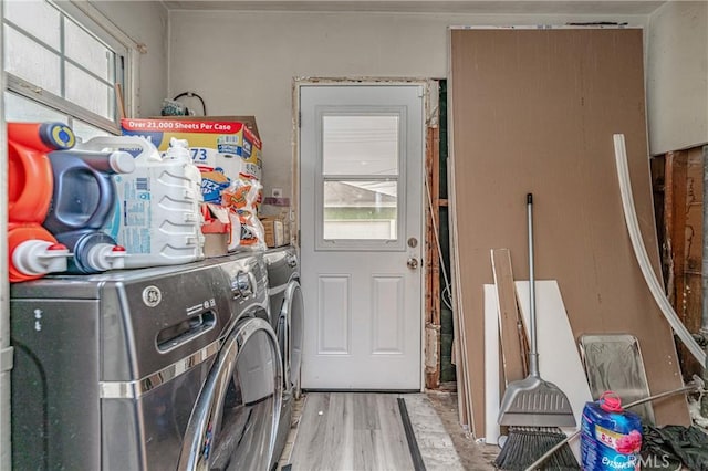 laundry area featuring plenty of natural light, washing machine and clothes dryer, and light hardwood / wood-style flooring