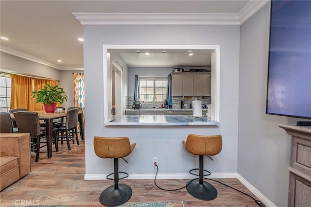 kitchen with decorative backsplash, ornamental molding, and light wood-type flooring