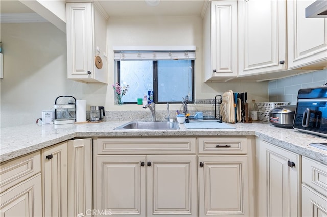 kitchen with exhaust hood, decorative backsplash, light stone counters, and sink