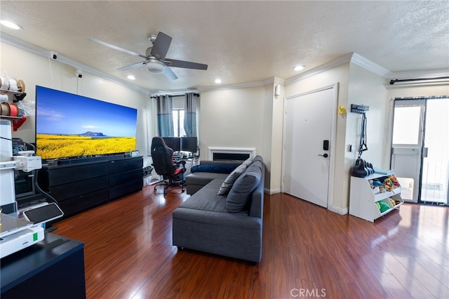 living room featuring a textured ceiling, ceiling fan, ornamental molding, and dark hardwood / wood-style floors