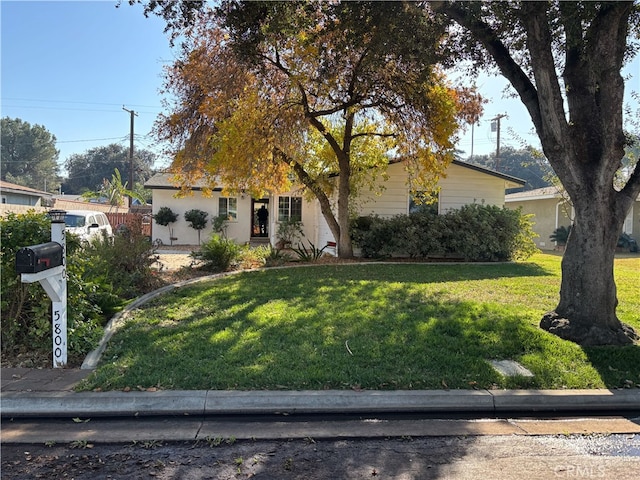 view of property hidden behind natural elements featuring a front lawn