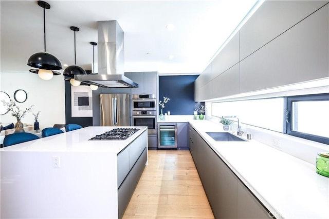 kitchen featuring island exhaust hood, stainless steel appliances, wine cooler, sink, and hanging light fixtures