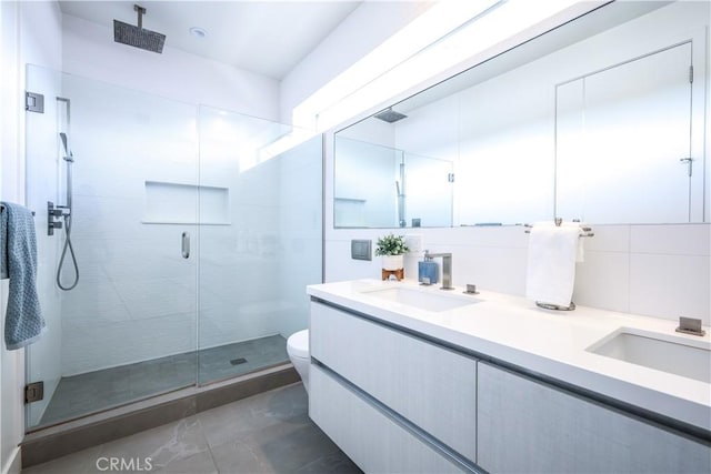 bathroom featuring toilet, tasteful backsplash, tile walls, walk in shower, and vanity