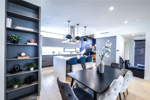 dining space with light wood-type flooring, built in features, sink, and a notable chandelier