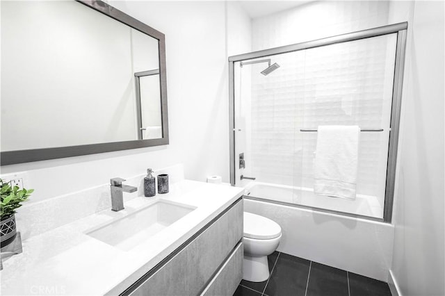 full bathroom with tile patterned floors, bath / shower combo with glass door, toilet, and vanity