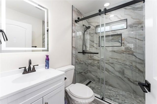 bathroom featuring toilet, a marble finish shower, and vanity