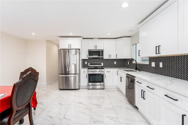 kitchen featuring stainless steel appliances, a sink, white cabinetry, marble finish floor, and light stone countertops