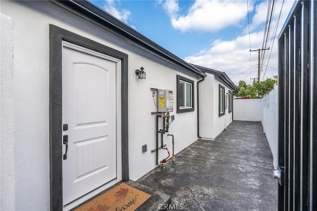 view of exterior entry featuring fence, a patio, and stucco siding