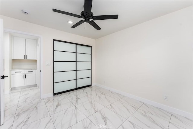 spare room featuring ceiling fan, marble finish floor, and baseboards